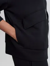 Campera negra de corte holgado con cierre bidireccional, cuello alto y bolsillos frontales.