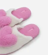 Pantufla abierta de diseño fluffy, confeccionada en poliéster suave de color blanco con una aplicación de corazón en relieve de color rosado. Cuenta con suela de goma termoplástica antideslizante y plantilla en tono rosado.
