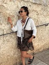 Bandolera de cuero marrón con detalles de tientos entrelazados en los laterales y correa ajustable.