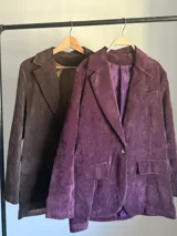 Blazer de corderoy con corte oversized, solapas de muesca y un solo botón frontal. Presenta bolsillos de parche en la parte delantera. Disponible en color marrón chocolate y morado merlot, ambos con forro interior.