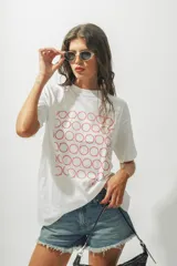 Remera de corte oversize color blanco, con cuello redondo y mangas cortas. Presenta un estampado frontal compuesto por múltiples círculos formados por puntos rojos.