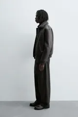 Cazadora oversize de efecto piel color negro, con interior y cuello solapa de pelo sintético gris a contraste. Cuenta con bolsillos de vivo en la cadera, acabados en rib elástico y cierre frontal con cremallera.