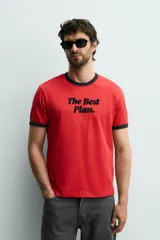 Camiseta de corte regular color rojo con cuello redondo y bordes de mangas en color azul marino. Presenta una estampa frontal con la frase 'The Best Plan.' en color azul marino.