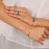 Anillo dorado con cinco piedras rectangulares de color azul.
