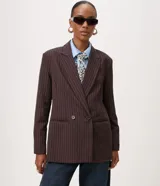 Blazer Cortelle oversized de raya diplomática marrón oscuro con líneas finas claras, cuello de solapa y doble botonadura frontal.