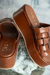 Sandalias de cuero Agnès Lenoble con plataforma plana y suela de madera, capellada con tiras doradas entrelazadas.