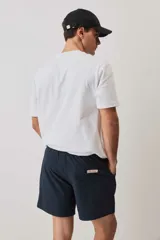 Short de baño de color azul marino, con cintura elástica y cordón ajustable blanco, bolsillos laterales y parche distintivo en el bajo. Presenta una textura con sutil efecto arrugado.