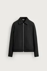 Cazadora de paño color negro de corte regular fit, con cuello solapa, bolsillos de vivo en la cadera, manga larga con puño abotonado y cierre frontal con cremallera metálica.