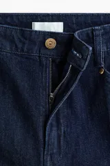 Pantalón de jean color azul oscuro con diseño de pernera ancha, talle alto, bolsillos diagonales al frente y raya marcada planchada en el centro de las piernas.