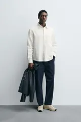 Camisa de corte relajado confeccionada en algodón, con cuello solapa, manga larga con puños abotonados, bolsillo de plastrón en el pecho y cierre frontal con botones.