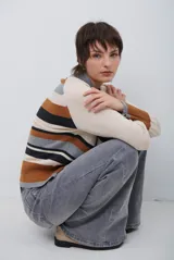 Polera de tejido de punto con diseño de rayas horizontales en tonos beige, marrón, gris y negro. Presenta cuello redondo y mangas largas con puños en contraste.
