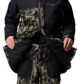 Campera de esquí Columbia con tecnología Omni-Tech impermeable y transpirable. Presenta un diseño bicolor con la parte superior en negro y la parte inferior con estampado camuflado. Incluye capucha ajustable compatible con casco, cierre frontal, múltiples bolsillos funcionales y ventilación en las axilas.