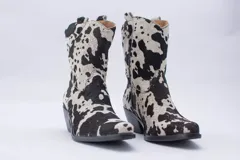 Botas de estilo western (texanas) de caña media, color blanco, confeccionadas en cuero. Presentan bordados decorativos en la caña y puntera cuadrada. Cuentan con cierre lateral y taco de altura media.