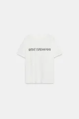 Camiseta oversize blanca de manga corta y cuello redondo, confeccionada en hilatura de algodón con detalle de texto estampado en contraste en el pecho.