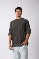 Remera oversize de algodón pesado con efecto lavado snow (gastado/vintage) en color gris oscuro. Presenta mangas amplias y costuras vistas.