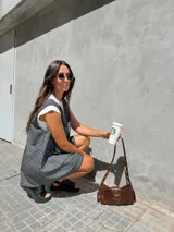 Vestido corto tipo jumper, confeccionado en tejido escocés a cuadros en tonos grises y blancos. Sin mangas, con escote en V y bolsillos delanteros. Se puede usar solo o con remera debajo.