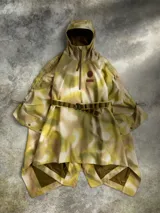 Poncho impermeable Columbia de edición especial inspirada en Star Wars, con diseño camuflado en tonos verde y beige, cierre frontal parcial con cremallera, capucha ajustable y cinturón integrado. Cuenta con la insignia de la Alianza Rebelde.