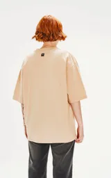 Remera de algodón premium color beige, con corte oversize, hombros caídos y cuello redondo.