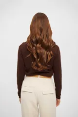 Buzo de punto fino color marrón, con cuello redondo y mangas largas, de corte ajustado al cuerpo.