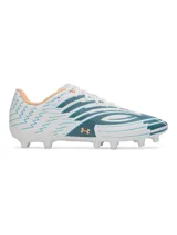 Championes de fútbol Under Armour Shadow Club 4 FG, con diseño en color blanco, detalles en azul petróleo y acentos en naranja. Presentan una parte superior sintética suave, cordones centrales y suela de TPU con tacos cónicos para tracción en césped natural.
