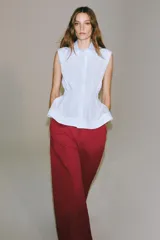 Camisa de algodón sin mangas con cuello solapa, diseño a rayas celestes y blancas, pliegues en la cintura y bajo evasé. Cierre frontal con botones ocultos.