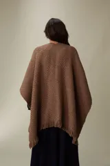 Ruana tejida en punto texturizado color marrón chocolate, con terminación de flecos en los bordes. Diseño inspirado en la vestimenta tradicional uruguaya, confeccionada en una mezcla de fibras suaves y ligeras.