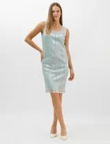Conjunto de dos piezas compuesto por un vestido corto de silueta recta en tejido plisado metalizado con escote redondo adornado con pedrería y perlas, y una chaqueta de gasa liviana con frente abierto, caída en cascada y mangas tres cuartos con puños metalizados.