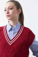 Chaleco de punto color bordó, con diseño de rombos y trenzas en relieve. Escote en V con ribete blanco y rojo.