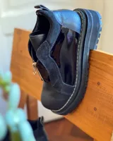 Botinetas de cuero combinadas en color negro y marrón, con diseño de paneles, cierre frontal y suela track dentada.