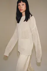 Jersey de punto calado, color crudo, con cuello redondo y manga larga.