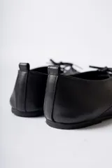 Zapato acordonado de cuero color negro, de diseño minimalista con punta cuadrada y silueta moderna.