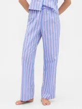 Pijama de dos piezas confeccionado en popelina, compuesto por una camisa de manga corta con cuello solapa y cierre frontal de botones, y un pantalón largo de corte recto con cintura elástica. Presenta un estampado integral de cerezas sobre fondo rosado.