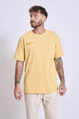 Remera blanca de algodón, corte holgado, con cuello redondo y un pequeño logo bordado en azul claro en el pecho.