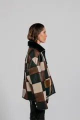 Buzo de cuero de oveja con diseño de parches cuadrados en tonos marrón, beige y verde oscuro. Presenta cuello alto con interior de piel sintética y cierre frontal.