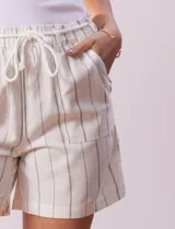 Short color crema con finas rayas verticales grises, pretina elastizada con cordón de ajuste, bolsillos delanteros y traseros.