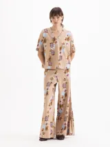 Pantalón East de tiro alto y botamanga amplia, confeccionado en morley liviano con estampado floreado. Presenta cintura estructurada con elástico y tablas en el lateral.