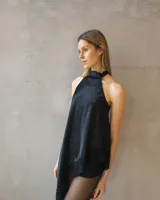 Blusa de satén negro con cuello halter y diseño asimétrico, con detalles de encaje en el borde inferior.