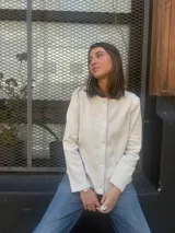 Cárdigan de lana color crudo, de tejido fino, con cuello redondo y cierre frontal de botones.