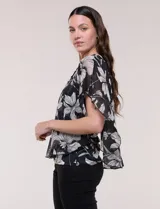 Blusa de gasa semitransparente con hilos de lúrex, diseño estampado floral en tonos blanco, gris y negro, silueta holgada tipo capa y escote redondo con detalle metálico.