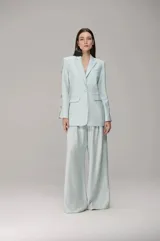 Blazer de corte sastre en color azul claro, con cierre frontal de un botón, solapas clásicas y mangas largas con aberturas laterales decoradas con cristales.