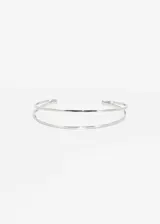 Brazalete abierto de metal plateado con doble línea.