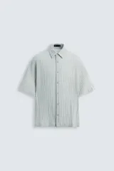 Camisa de manga corta con cuello solapa, confeccionada en tejido de mezcla de lyocell con textura de efecto arrugado y cierre frontal de botones.