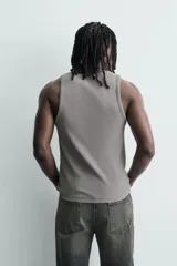 Musculosa de corte slim fit confeccionada en tejido de algodón con elasticidad, cuello redondo amplio y efecto lavado.