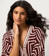 Vestido largo de viscosa con estampado geométrico en tonos bordó y blanco, escote en V y mangas cortas. Incluye un cinturón de cuerda para ajustar la cintura y una abertura frontal.