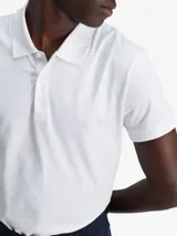 Chomba de corte slim confeccionada en una mezcla de algodón compacto, poliéster y elastano. Presenta cuello clásico, cierre frontal de botones, mangas cortas y dobladillo ventilado. Incluye un discreto logotipo monograma bordado en el pecho.