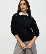 Buzo negro de algodón con cuello camisero blanco sobrepuesto, mangas largas con puños ajustados y aplicación de mini beads brillantes distribuidas por el frente.