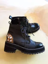Borcego de cuero negro con cordones, suela de plataforma y detalles de arte pintado a mano en el talón.