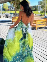 Vestido largo sin mangas con escote en V pronunciado, de corte amplio y fluido, con estampado abstracto en tonos rosados, marrones y blancos, y un cordón trenzado ajustable en la cintura.