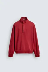 Sudadera de corte relajado color rojo con efecto lavado. Presenta cuello subido con cierre frontal de botones a presión, manga larga y puños y ruedo terminados en rib.