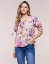 Blusa de gasa liviana con estampado floral en tonos violeta y rosado, cuello redondo y mangas cortas con detalle de lazo en los puños.